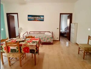 Séjour lumineux avec table à manger et lit dans un appartement en Sicile, bien immobilier proposé par CET Invest.