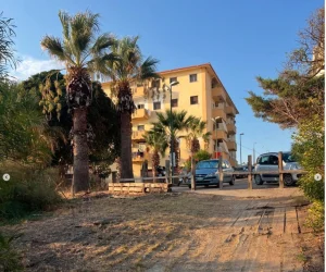 Immeuble résidentiel en Sicile entouré de palmiers, avec appartements proposés à la vente.