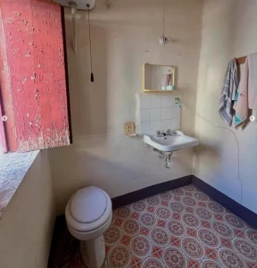 Salle de bain ancienne avec lavabo et carrelage rétro dans une maison sicilienne.